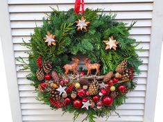 a christmas wreath hanging on the side of a door with ornaments and deers around it