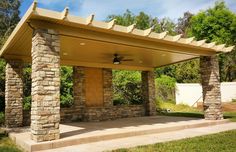 a patio covered with stone pillars and a ceiling fan