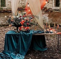 a table with flowers and candles is set up in front of an old brick building