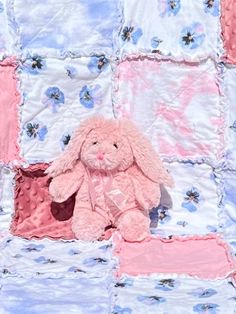 a pink stuffed animal sitting on top of a quilt