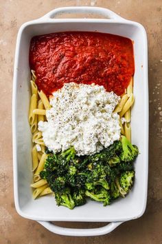 a white dish filled with pasta and broccoli covered in tomato sauce, fettuccine and parmesan cheese