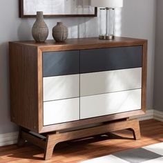 a white and black cabinet with two vases on top of it next to a mirror