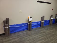 two seagulls are sitting on posts in front of a wall with blue tarp