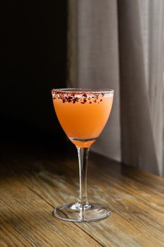 an orange drink sitting on top of a wooden table