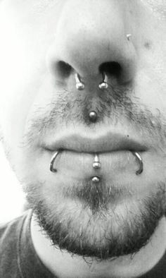 a man with piercings on his nose is looking at the camera