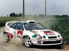 an autographed photo of a car driving down a dirt road