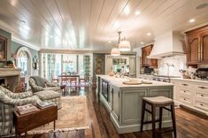 a large open concept kitchen and living room with wood flooring, white painted walls and ceiling