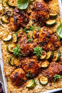 chicken and zucchini on top of rice in a white dish with green garnish