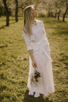 a woman in a white dress is standing in the grass