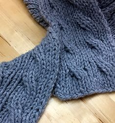 a gray knitted scarf laying on top of a wooden floor