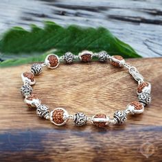 🌿 Welcome to a world of tranquility and spiritual connection with our stunning Five Face Rudraksha Beads Silver Capped (925 Sterling Silver) Bracelet, featuring serene Om charm delicately nestled between each bead! 🕉️✨ Crafted with care and precision, this bracelet embodies the perfect balance of elegance and spiritual significance. Each Rudraksha bead, adorned with durable sterling silver caps, symbolizes harmony, protection, and inner peace. 📿💖 💫 But this bracelet offers more than just ae Rudraksha Bracelet, Om Bracelet, Om Charm, Rudraksha Beads, Silk Gifts, Silver Caps, Mala Bracelet, Spiritual Connection, Bracelet Sterling Silver