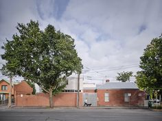 a person sitting on a bench in front of a red brick building with two trees