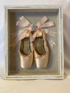 a pair of pink ballet shoes in a shadow box with ribbon and star decorations on the side