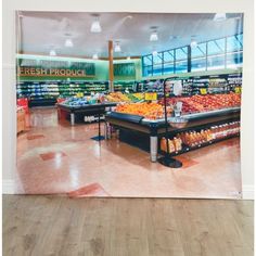 an empty grocery store with fresh produce displayed on the wall and in the background is a large poster