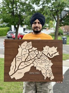 a man holding up a wooden sign with the map of india in front of him