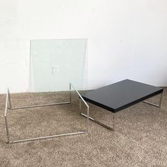 two tables sitting on top of carpeted floor next to each other in front of a white wall