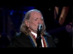 an older man with long hair singing into a microphone