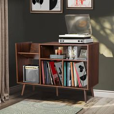 a book shelf with books and an open laptop computer on top, in front of two framed pictures