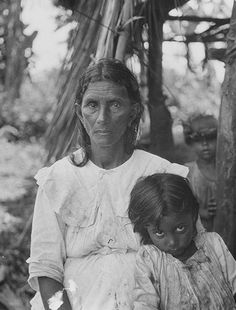 an old black and white photo of a woman holding a child