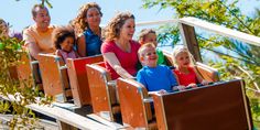 a group of people riding on top of a wooden roller coaster at a theme park