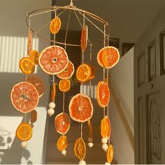 an orange mobile hanging from the ceiling in front of a doorway with sunlight coming through it