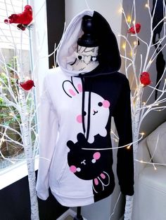 My original design, BunyingBunyang, as unisex hoodie. The hoodie has a soft outside with a vibrant print, and an even softer brushed fleece inside. The hoodie has a relaxed fit. * 70% polyester, 27% cotton, 3% elastane * Fabric weight: 8.85 oz/yd² (300 g/m²) * Soft cotton-feel fabric face * Brushed fleece fabric inside * Double-lined hood with design on both sides * Unisex style * Overlock seams * Comes with drawstrings White Hooded Hoodie With Cartoon Print, White Hoodie With Cartoon Print, Black Hooded Hoodie With Cartoon Print, Kawaii Hooded Sweatshirt With Graphic Print, Black Hoodie With Cartoon Print, Black Cartoon Print Hoodie, Black Kawaii Hoodie For Winter, Black Kawaii Hoodie Sweatshirt, Kawaii Hoodie Sweatshirt With Drawstring