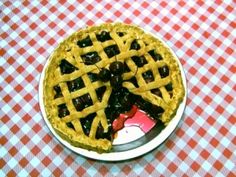 a plate with a pie on it sitting on top of a checkered table cloth