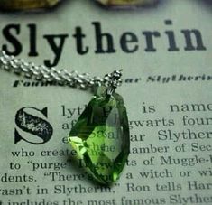 a green necklace sitting on top of an open book