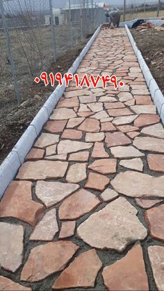 a walkway made out of stones in front of a fence