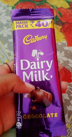 a person holding a bar of dairy milk chocolate