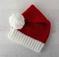 a red and white knitted hat with a pom - pom on top