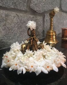 there is a small statue with flowers in the bowl on the table next to it