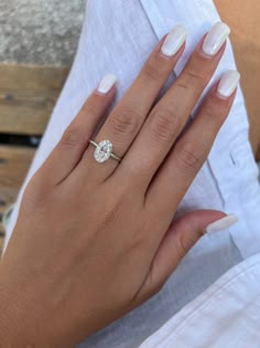 a woman's hand with a white manicured nail polish and a diamond ring