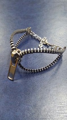 two bracelets with silver beads and metal clasps on a blue tablecloth surface