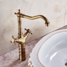 a white sink sitting next to a gold faucet