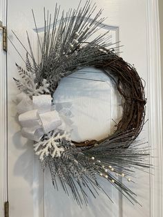 a wreath is hanging on the front door with snowflakes and silver ribbon around it