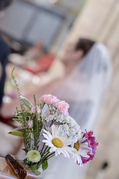 a vase filled with flowers sitting on top of a table next to a bride and groom