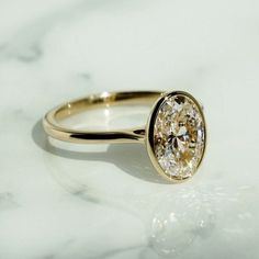 a close up of a ring on a marble surface with the center stone in yellow gold