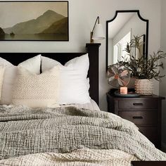 a bed with pillows and blankets on top of it next to a dresser in a bedroom