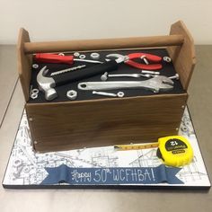 a birthday cake made to look like a box with tools in it and the words happy 50th written on top