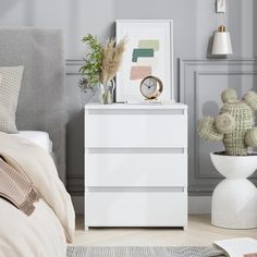 a white dresser sitting next to a bed in a bedroom