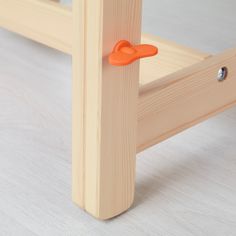 a close up of a wooden bed frame with an orange plastic handle on the end