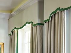 a living room with two windows and green trim on the curtain valances, along with an ornate window sill