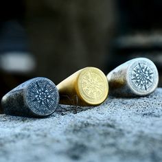 three gold and silver buttons sitting on top of a stone slab next to each other