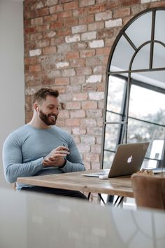 a man sitting at a table looking at his cell phone and laptop computer in front of him