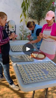 three women standing around a table with doughnuts on it