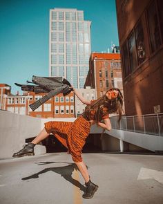 a woman in an orange and black dress is doing a trick on a skateboard