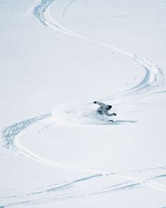 a person riding skis down the side of a snow covered slope on a hill