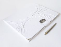 a white notebook and pen sitting on top of a table