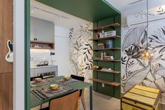 a kitchen with green and white wallpaper next to a dining room table in front of a bookshelf